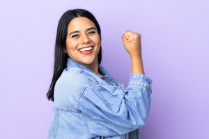 Junge Frau mit erhobenem Arm, lächelt in die Kamera