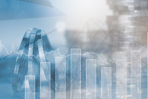 Im Vordergrund Linien- und Säulendiagramm, im Hintergrund sind unscharf Münzen und Geldstapel zu sehen