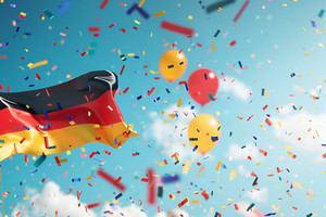 Deutsche Flagge mit Luftballons und Konfetti vor blauem Himmel